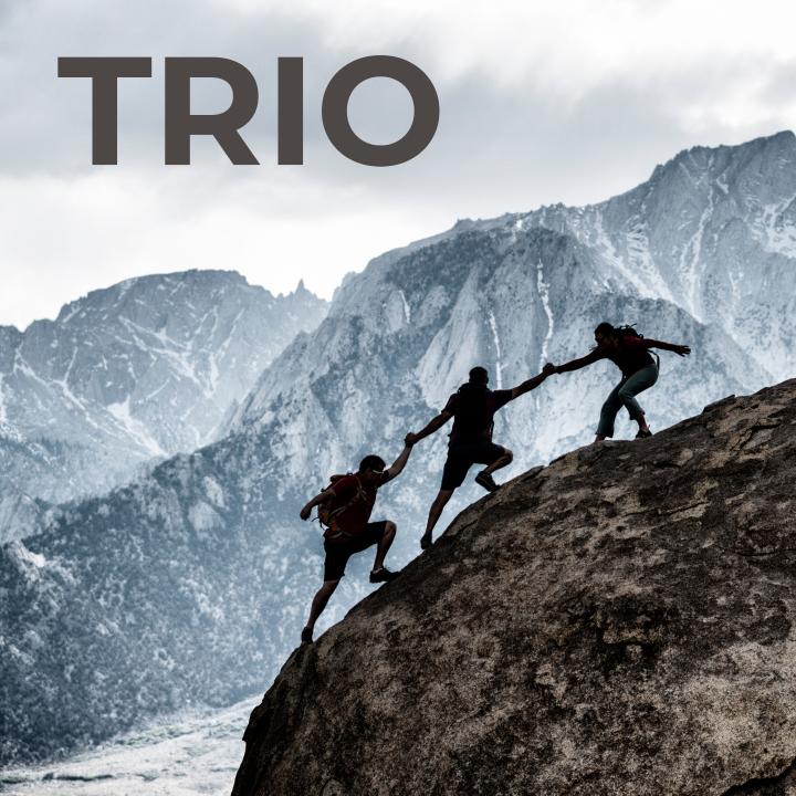 three hikers helping each other up a mountain