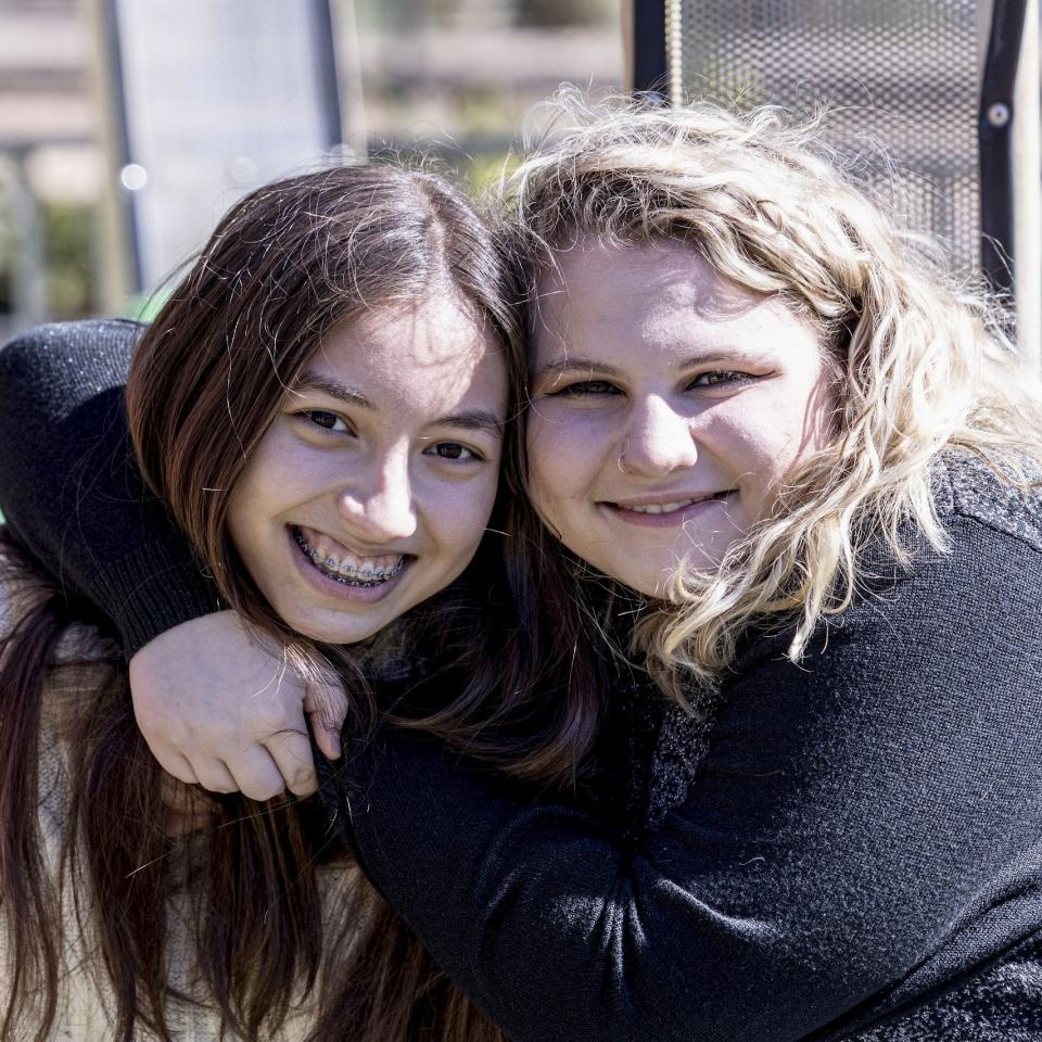 Teenage friends smiling with arms around each other